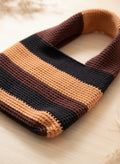Close-up of the brown and orange striped crochet tote bag, showing the detailed stitch work and the texture of the yarn.