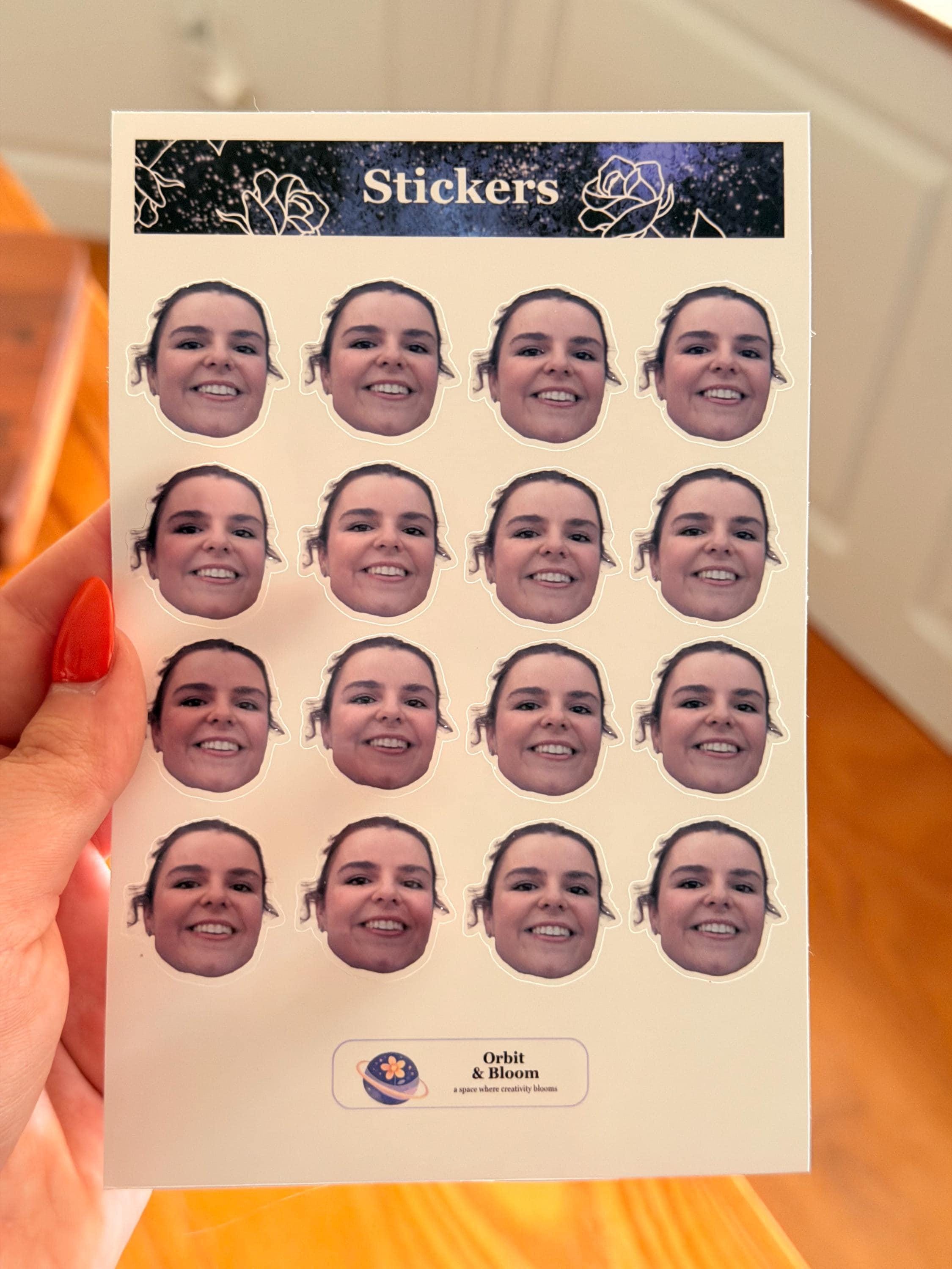 A person holding a sticker sheet featuring a grid of sixteen identical face stickers against a white background.