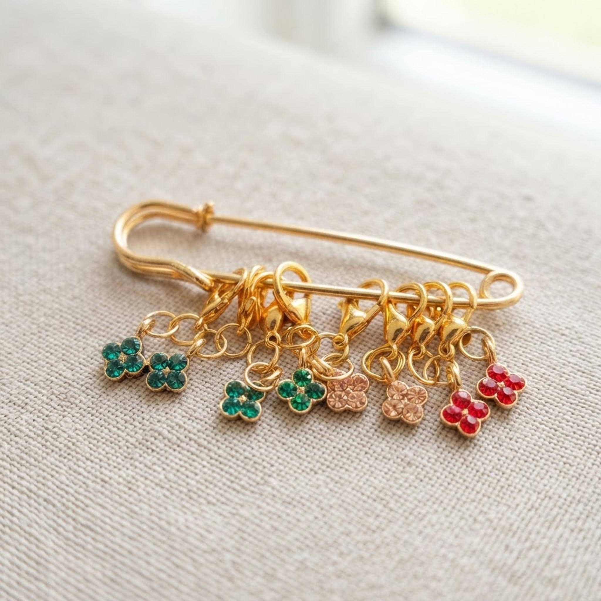 Close up of floral stitch markers featuring enamel daisies and gold clasps.