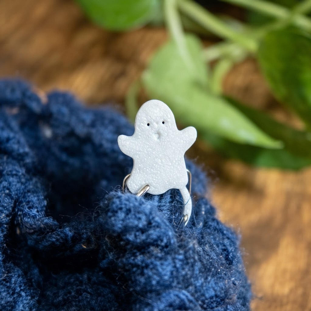 Close-up of a white ghost stitch marker clipping into dark blue crochet stitches.